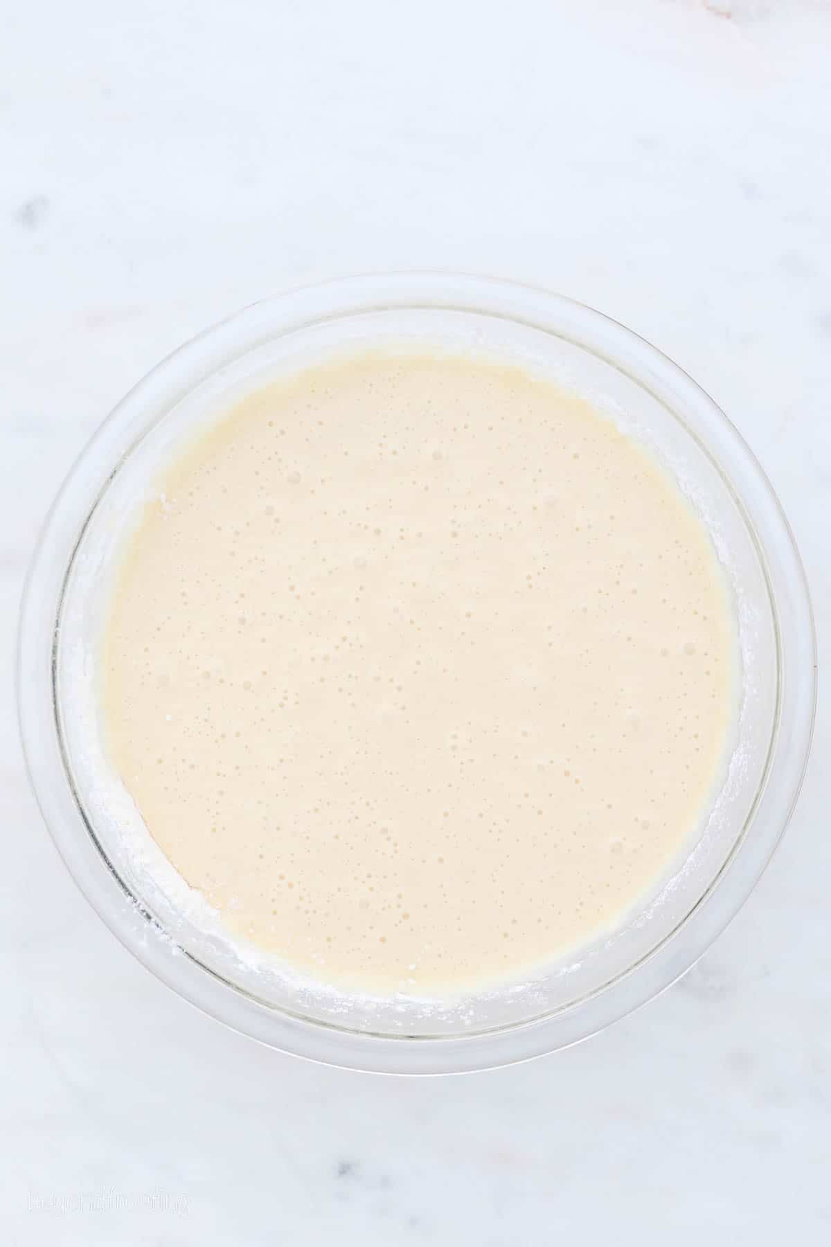 This moist vanilla cake recipe is perfectly sweet and fluffy and covered with creamy vanilla frosting. It's the best cake for any occasion! Vanilla cake batter in a glass mixing bowl.