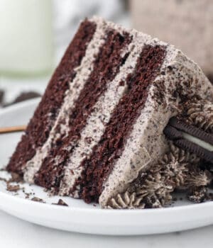 A slice of Oreo chocolate cake garnished with Oreos on a white pate.