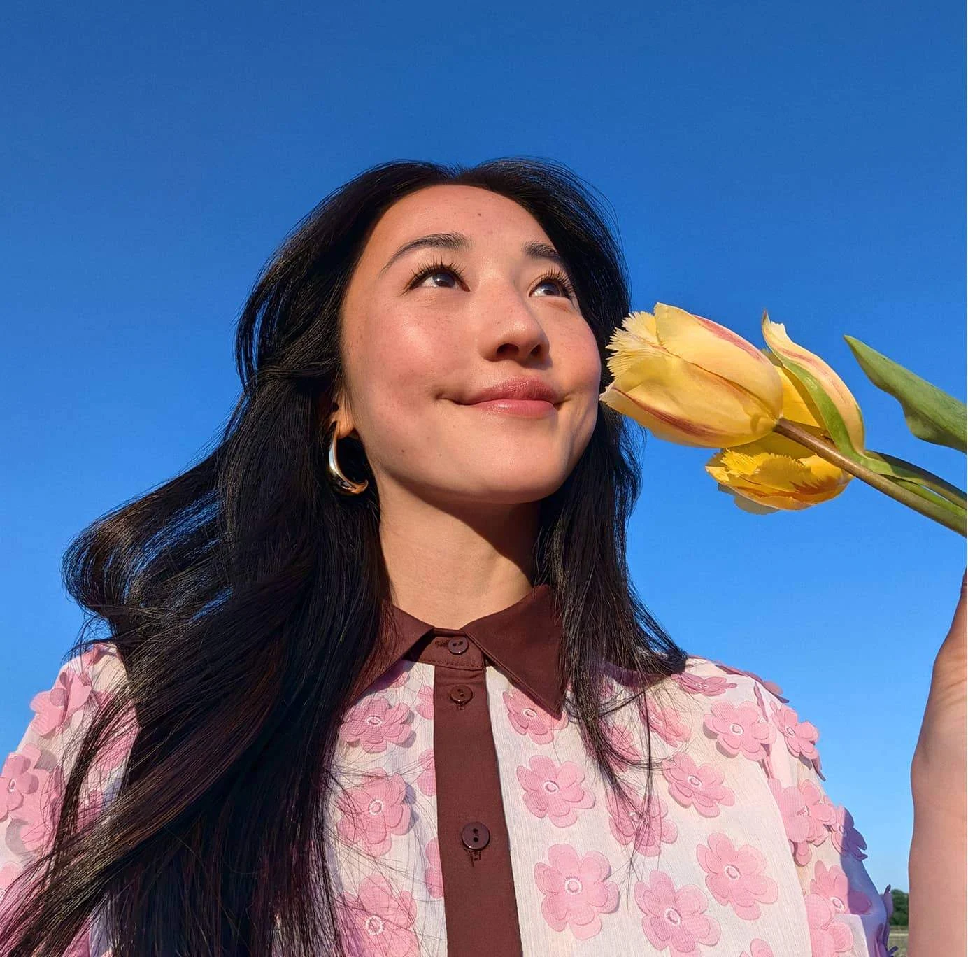 A person taking a selfie with a yellow flower.