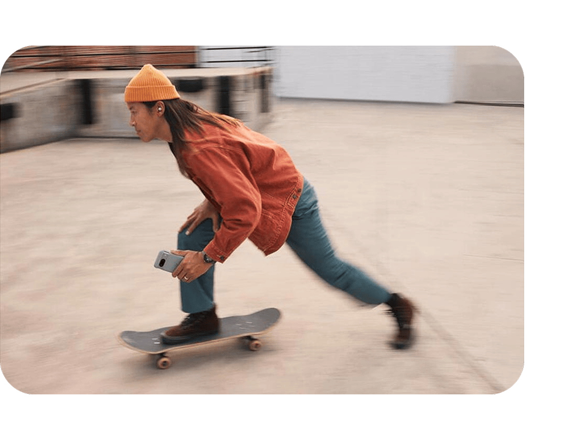 An individual riding on a skateboard with a Pixel 9 device in Moonstone color in their hand