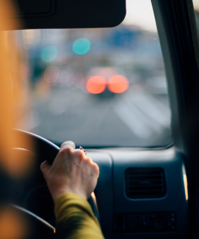 An image of a woman hands on wheel driving across the city