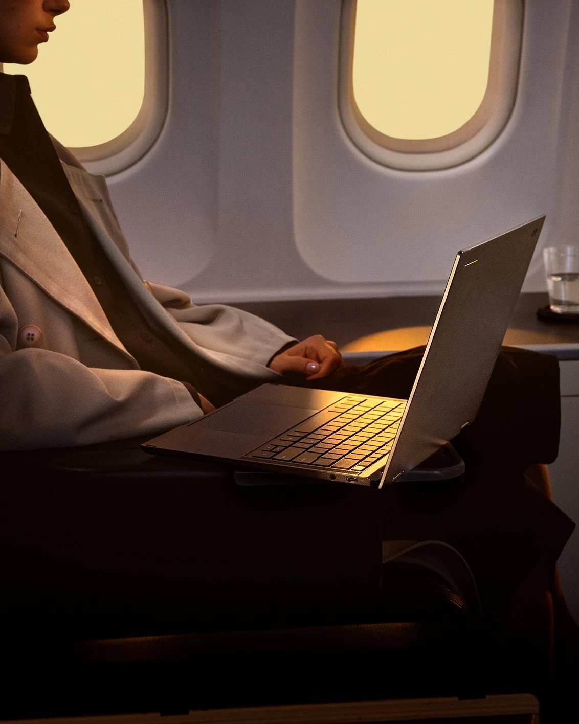 A passenger using an Acer Googlebook while seated in an airplane cabin next to a window.