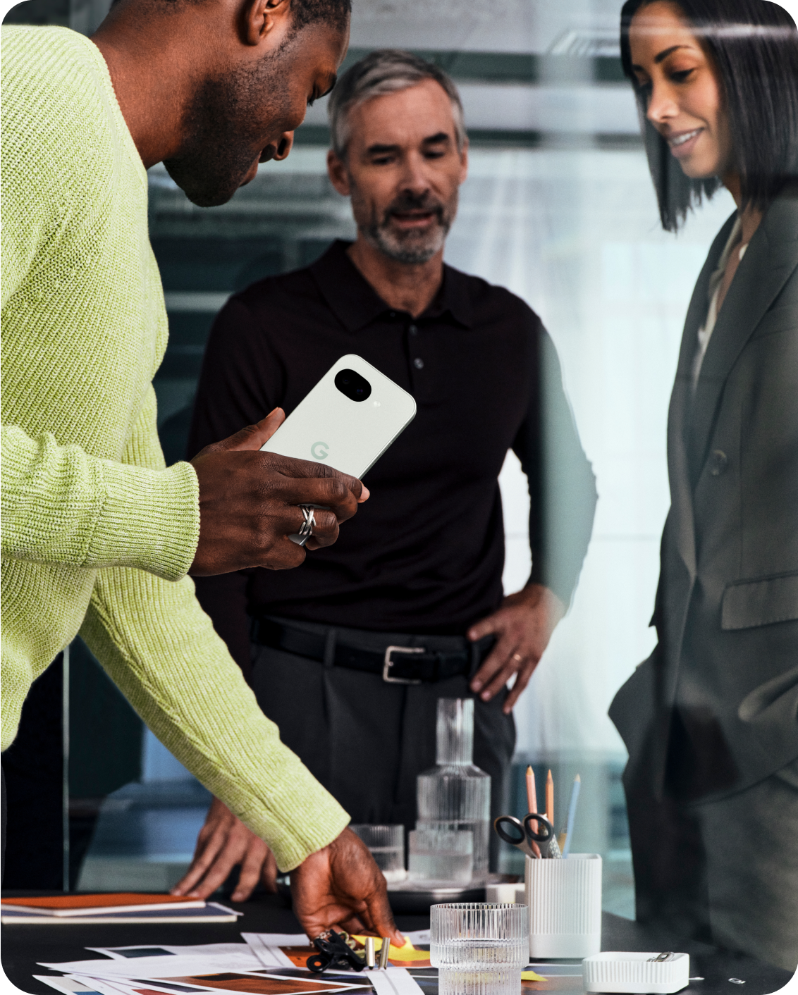 A team of three people using a Pixel 10a while looking at some designs.