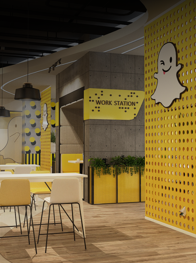 Modern office break area with a Snapchat ghost logo, yellow perforated walls, concrete accents, and cafe-style seating.