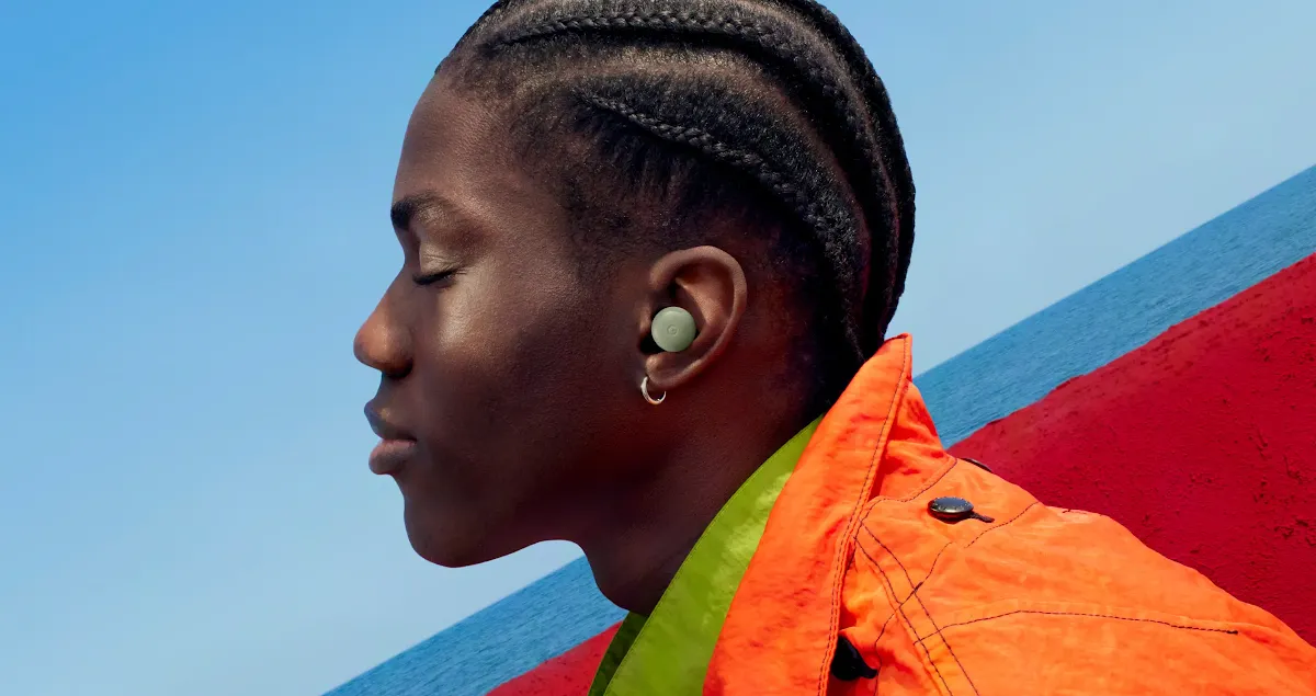 A person wearing Pixel Buds and an orange jacket.