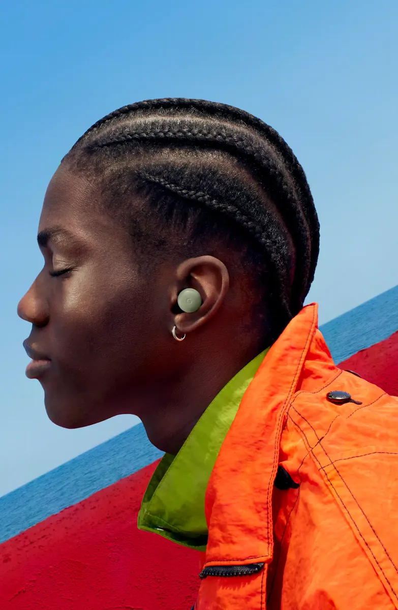 A person wearing Pixel Buds and an orange jacket.