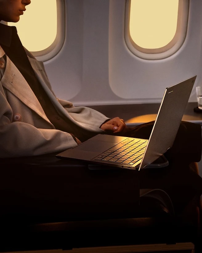 A passenger using an Acer Googlebook while seated in an airplane cabin next to a window.