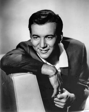 A smiling man in a suit leans on a chair in a vintage studio photo. — Singer Picture