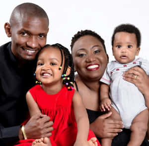 A happy African family of four posing for a studio portrait with bright smiles. — Dj Picture
