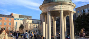 Students walking near a white columned rotunda labeled George Washington on a sunny campus day. — Art Deco Picture