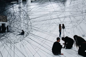 Visitors explore a large wire art installation in a white gallery. — Art Picture