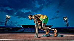 Athlete poised at starting blocks on a track under stadium lights at night.