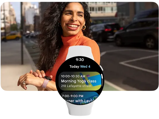 The smartwatch user is standing on the sidewalk in a downtown city area and smiling while looking in the direction that the Google Maps watch is navigating toward.