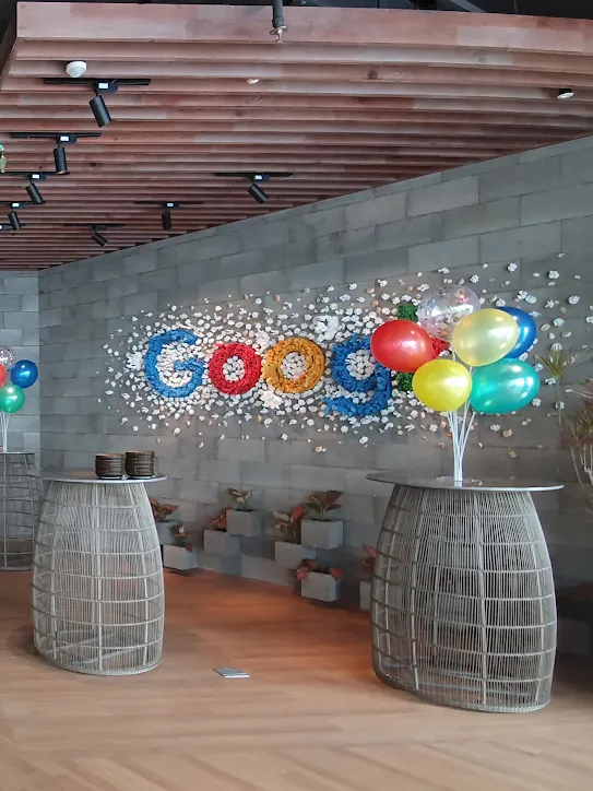 Ein Google-Büro, das für eine Feier dekoriert ist. Auf Tischen liegen bunte Ballons, von der Decke hängen große Seidenschirme.