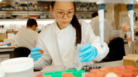 A young researcher works in a lab, handling test tubes.